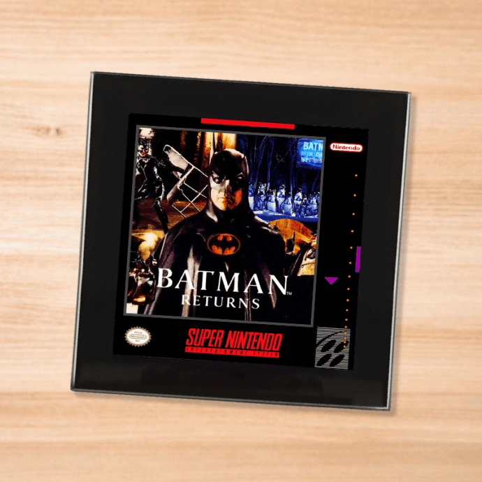 Black glass Batman Returns coaster on a wood table