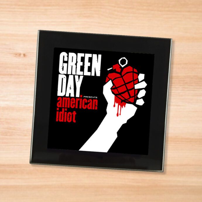Black glass Green Day - American Idiot coaster on a wood table