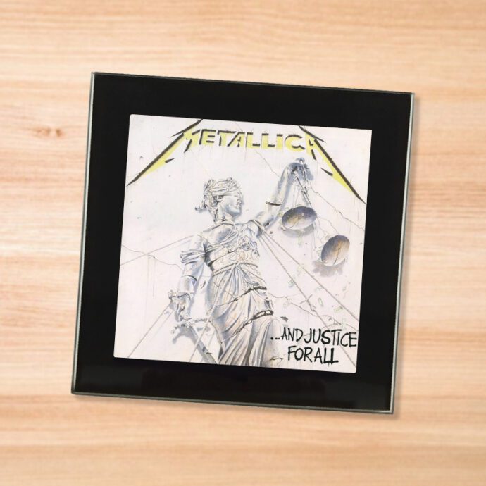 Black glass Metallica - And Jutsice For All coaster on a wood table