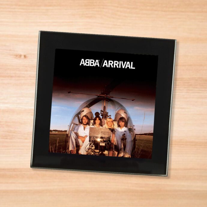 Black glass ABBA - Arrival coaster on a wood table