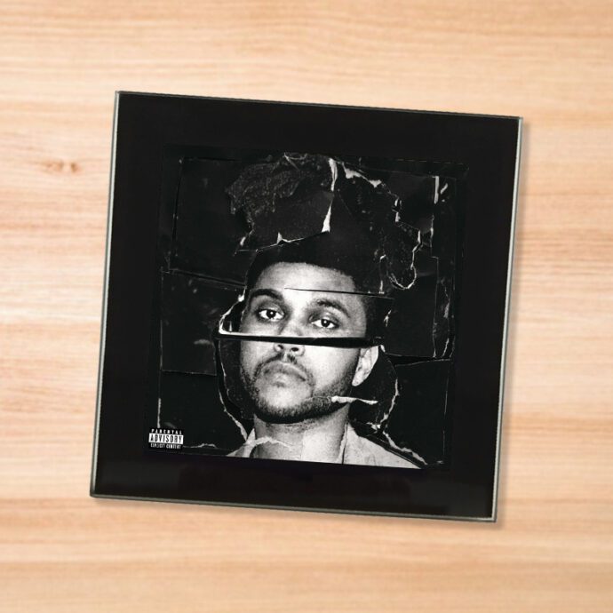 Black glass The Weeknd - Beauty Behind the Madness coaster on a wood table