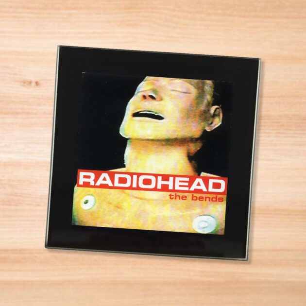 Black glass Radiohead - The Bends coaster on a wood table