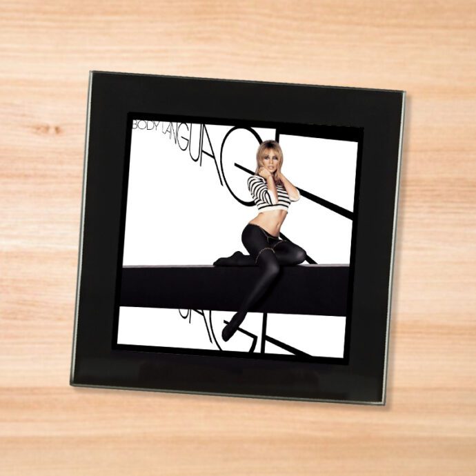 Black glass Kylie - Body Language coaster on a wood table