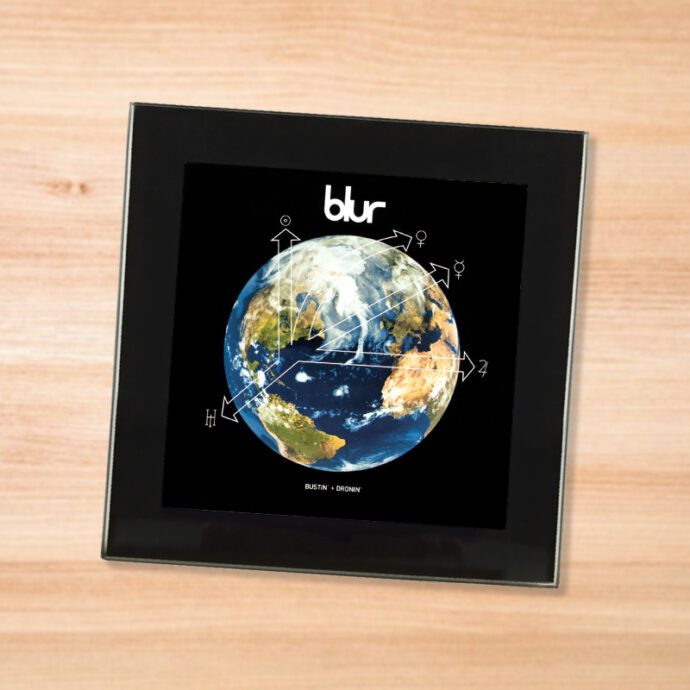 Black glass Blur - Bustin and Dronin coaster on a wood table