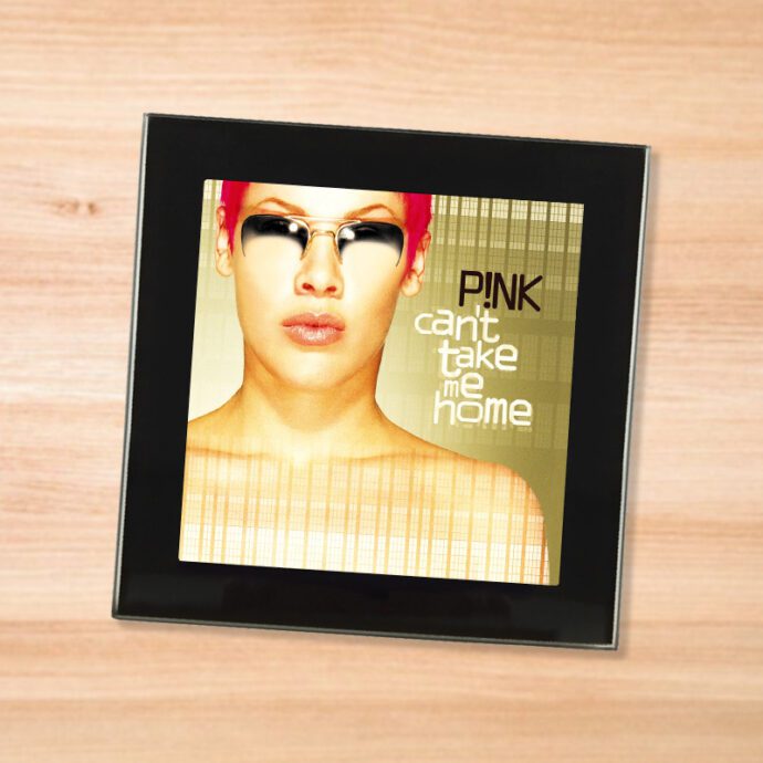 Black glass Pink - Can't Take Me Home coaster on a wood table