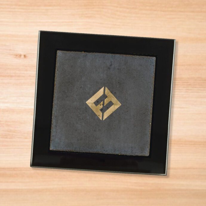 Black glass Foo Fighters - Concrete and Gold coaster on a wood table