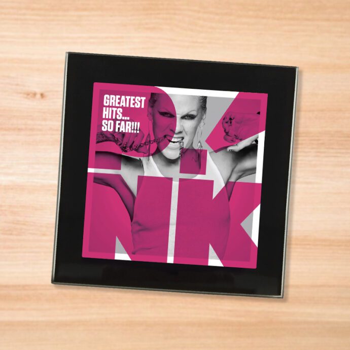 Black glass Pink - Greatest Hits So Far coaster on a wood table