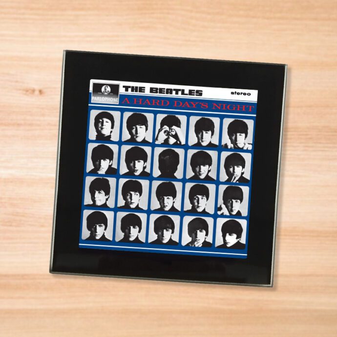 Black glass The Beatles - A Hard Day's Night coaster on a wood table