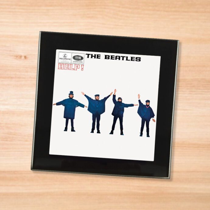 Black glass The Beatles - Help! coaster on a wood table