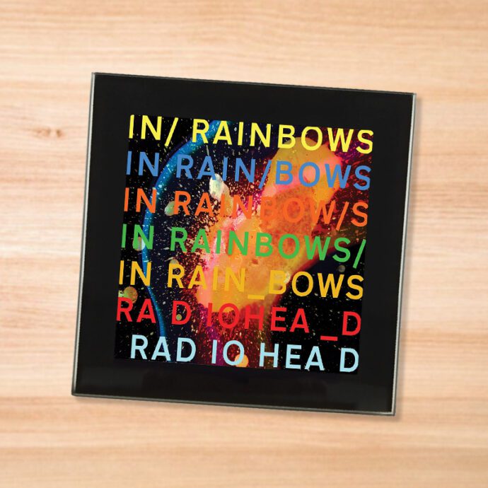 Black glass Radiohead - In Rainbows coaster on a wood table