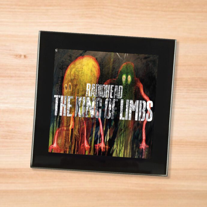Black glass Radiohead - King of Limbs coaster on a wood table