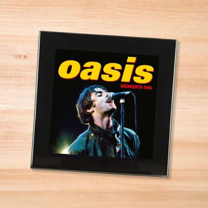 Black glass Oasis - Knebworth 1996 coaster on a wood table