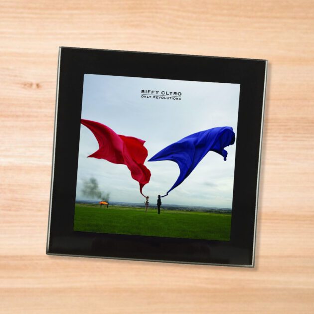 Black glass Biffy Clyro - Only Revolutions coaster on a wood table