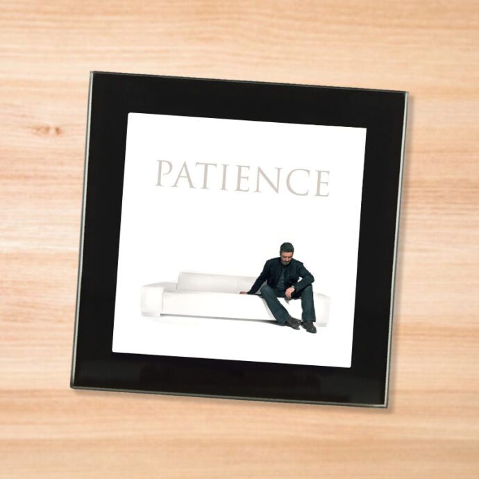 Black glass George Michael - Patience coaster on a wood table
