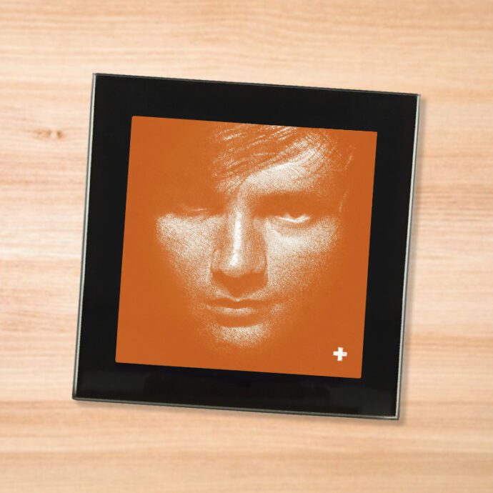 Black glass Ed Sheeran - Plus coaster on a wood table