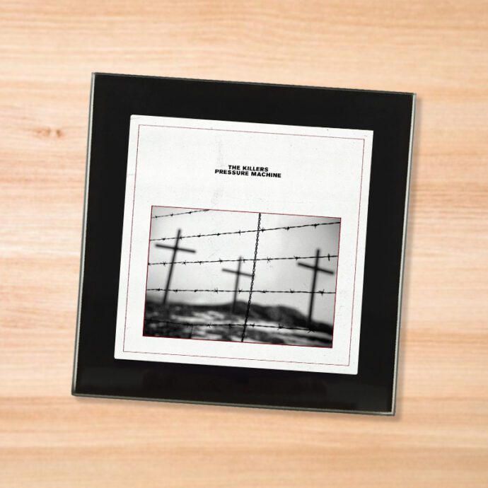 Black glass The Killers - Pressure Machine coaster on a wood table