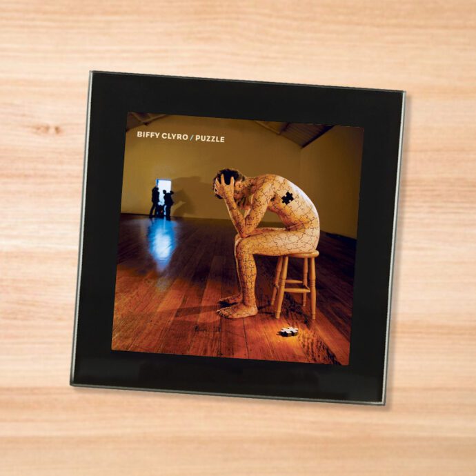 Black glass Biffy Clyro - Puzzle coaster on a wood table