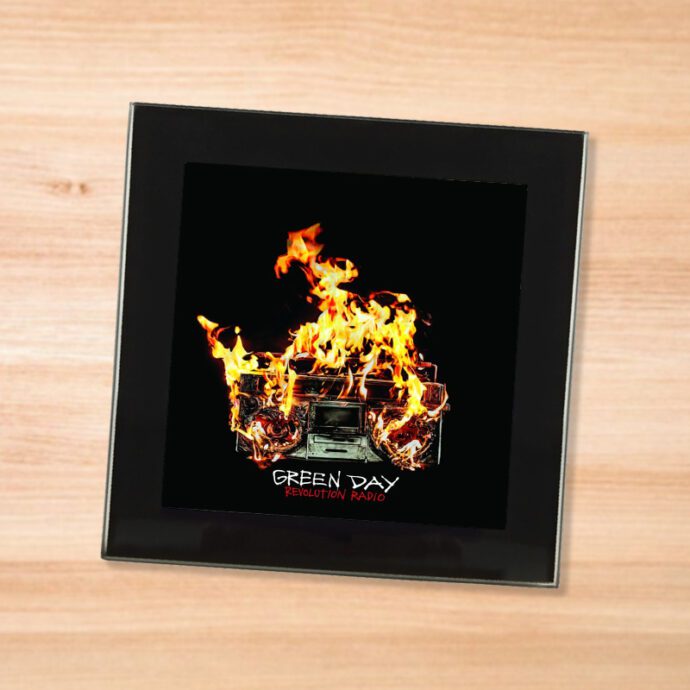 Black glass Green Day - Revolution Radio coaster on a wood table