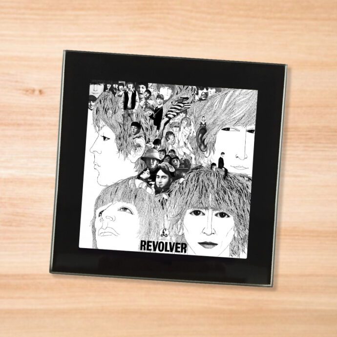 Black glass The Beatles - Revolver coaster on a wood table