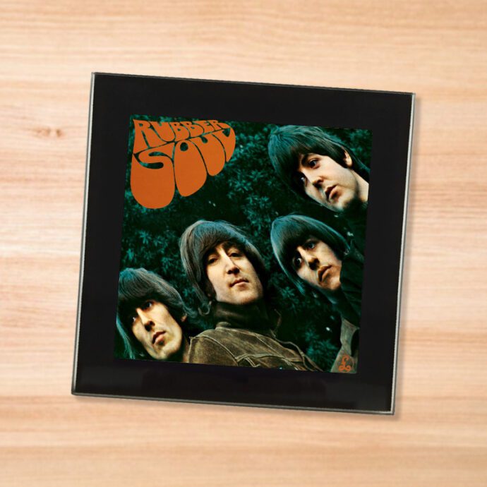 Black glass The Beatles - Rubber Soul coaster on a wood table