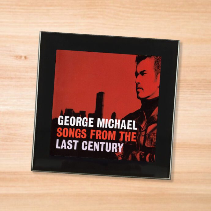 Black glass George Michael - Songs From the Last Century coaster on a wood table