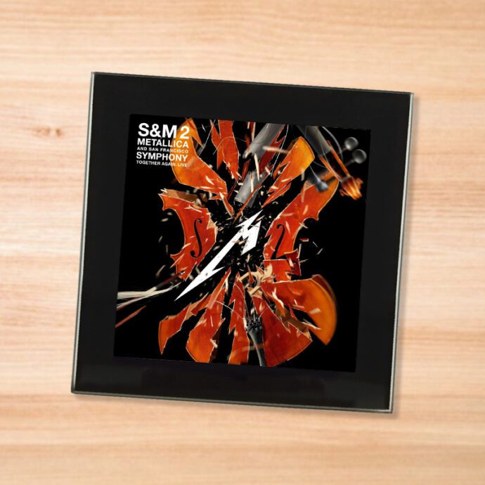Black glass Metallica - S&M2 coaster on a wood table