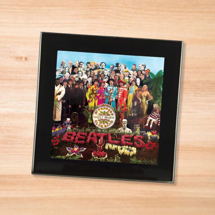 Black glass The Beatles - Sgt. Pepper's coaster on a wood table