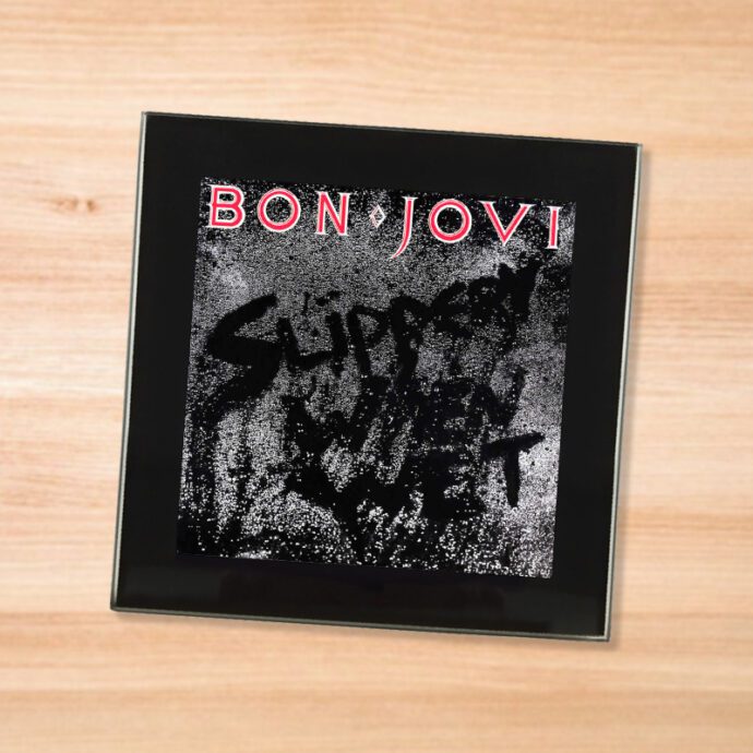 Black glass Bon Jovi - Slippery When Wet coaster on a wood table