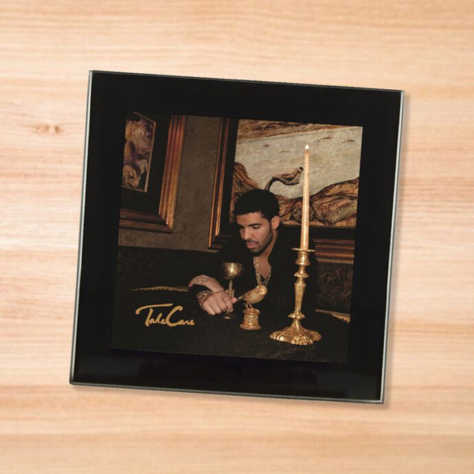 Black glass Drake - Take Care coaster on a wood table