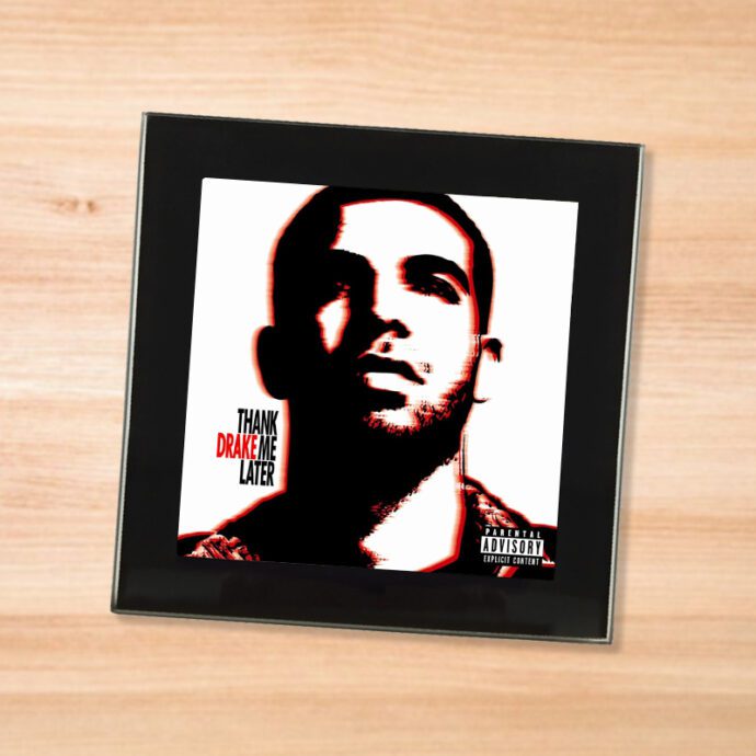 Black glass Drake - Thank Me Later coaster on a wood table