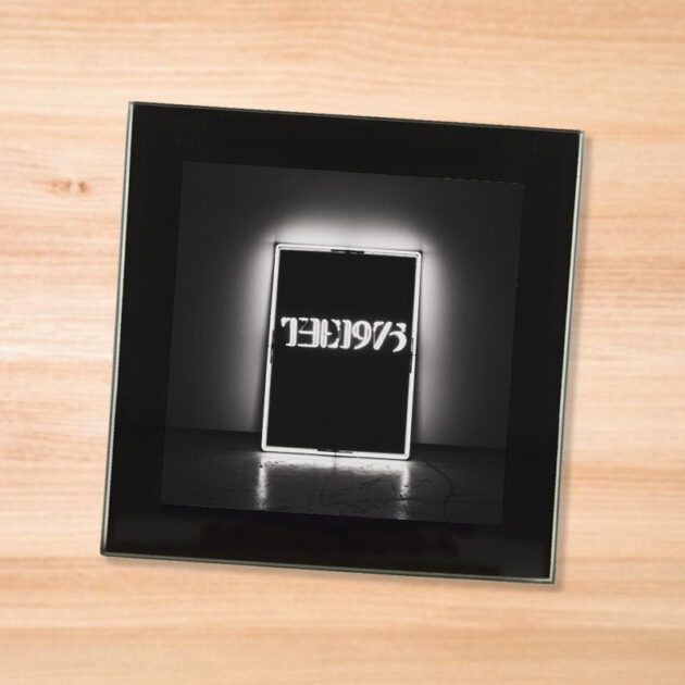 Black glass The 1975 album coaster on a wood table