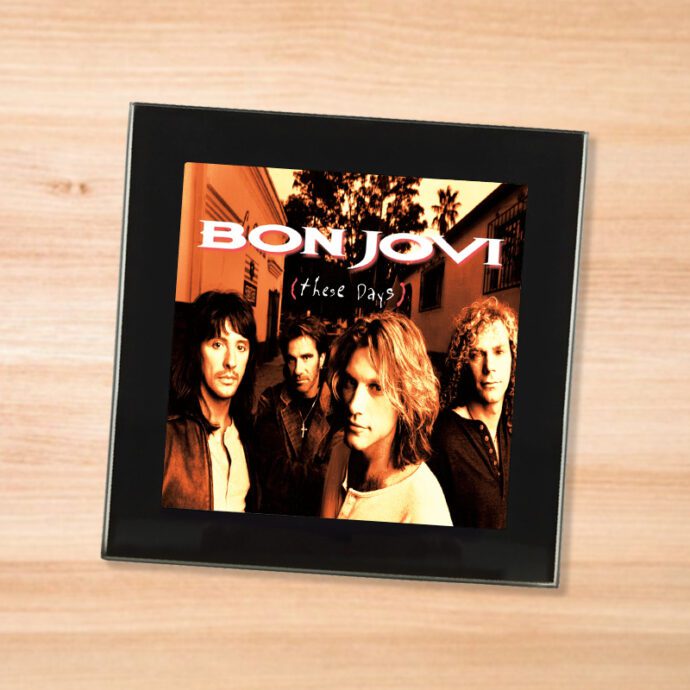 Black glass Bon Jovi - These Days coaster on a wood table