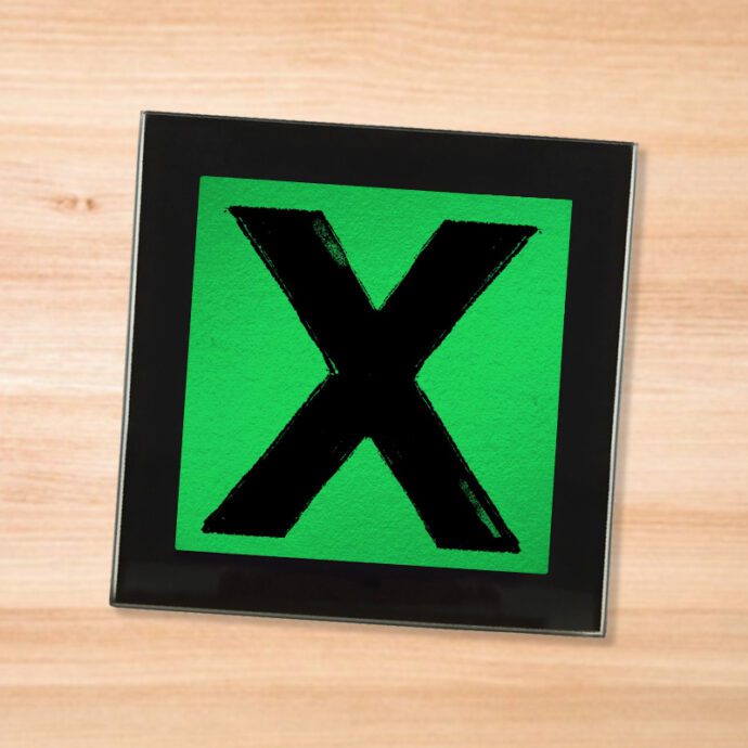 Black glass Ed Sheeran - X coaster on a wood table