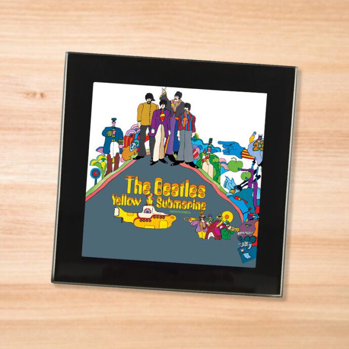 Black glass The Beatles - Yellow Submarine coaster on a wood table