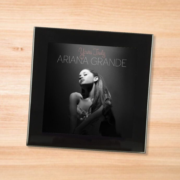 Black glass Ariana Grande - Yours Truly coaster on a wood table