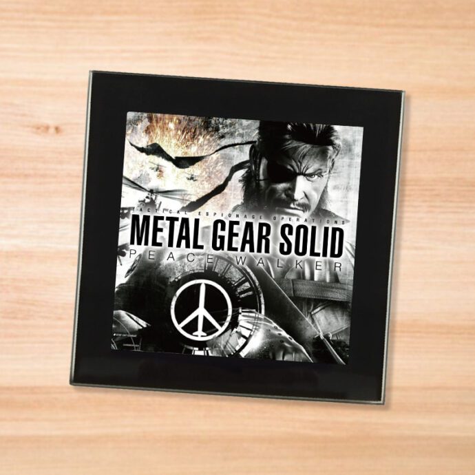 Black glass Metal Gear Solid Peace Walker coaster on a wood table