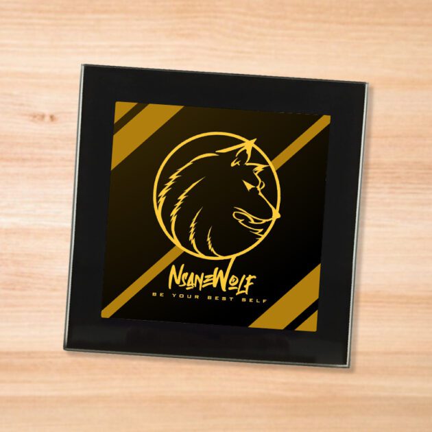 Black glass NsaneWolf - Be Your Best Self (Gold) logo coaster on a wood table