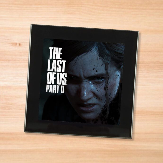 Black glass The Last Of Us Part 2 coaster on a wood table