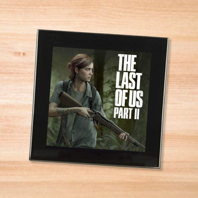Black glass The Last Of Us Part 2 coaster on a wood table