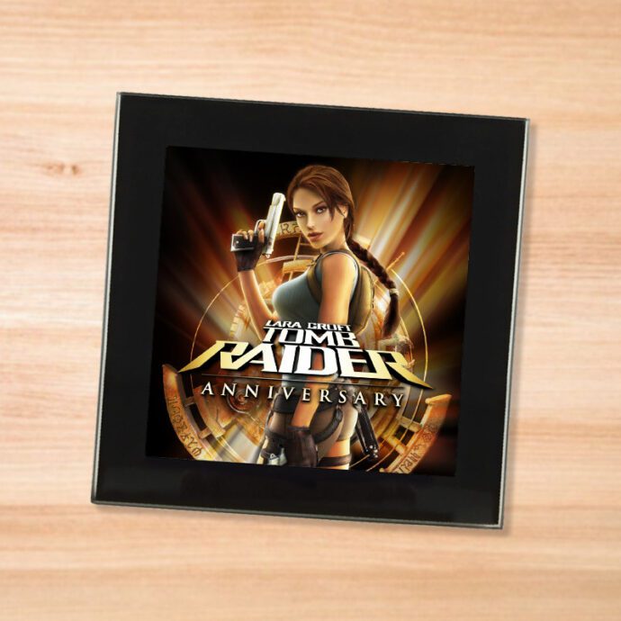 Black glass Tomb Raider Anniversary coaster on a wood table