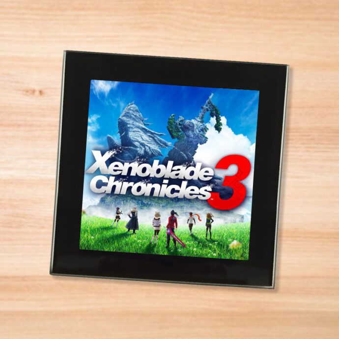 Black glass Xenoblade Chronicles 3 coaster on a wood table