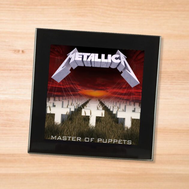 Black glass Metallica - Master of Puppets coaster on a wood table