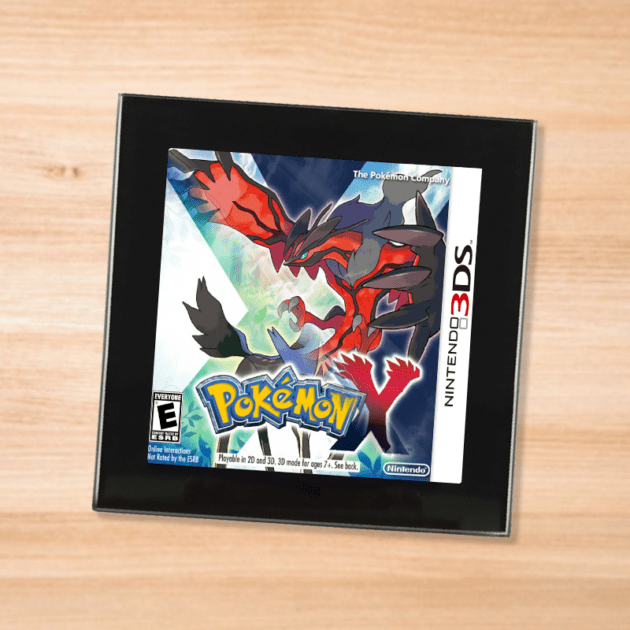 Pokemon Y black glass coaster on a wood table